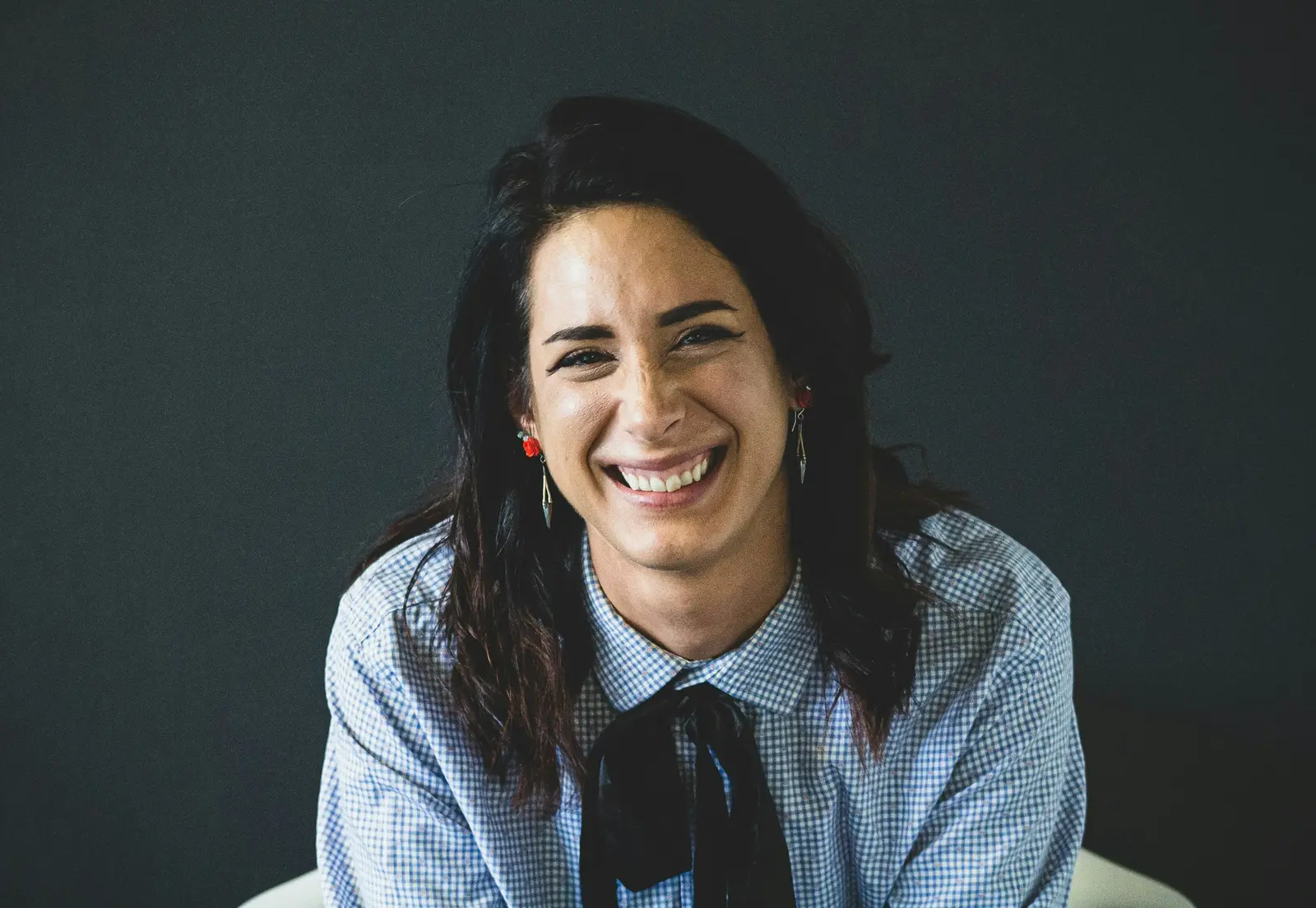 A photographer lighting a staff headshot against a grey backdrop in an office meeting room