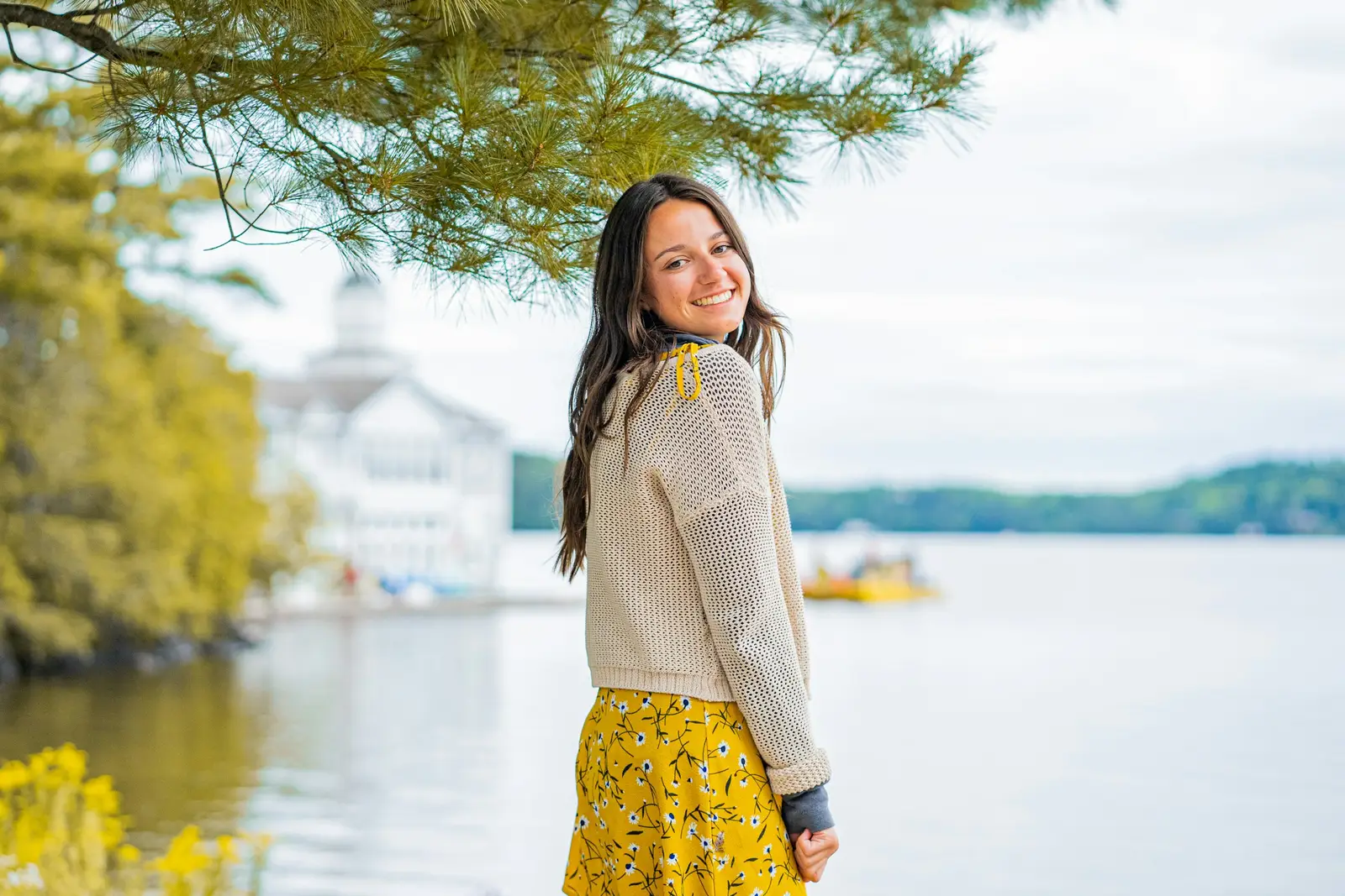 A traveller smiling on a riverside walkway with London landmarks behind her