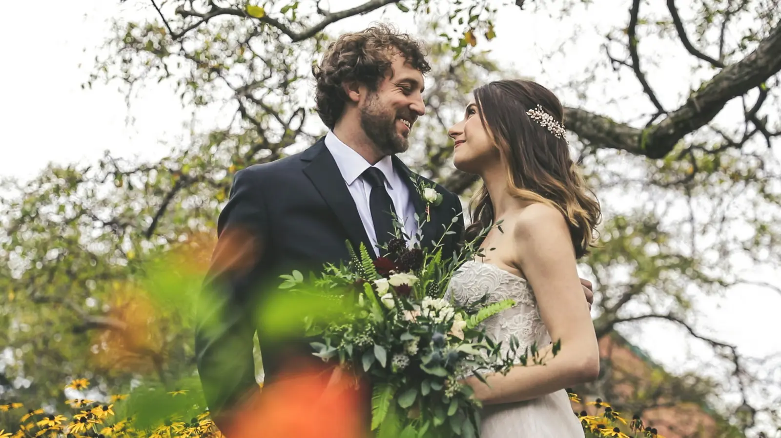 A bride and groom walking out of a stone church as guests throw confetti