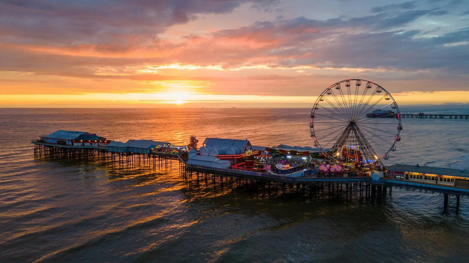 Blackpool Tower above the promenade at dusk, with the Illuminations lit along the seafront