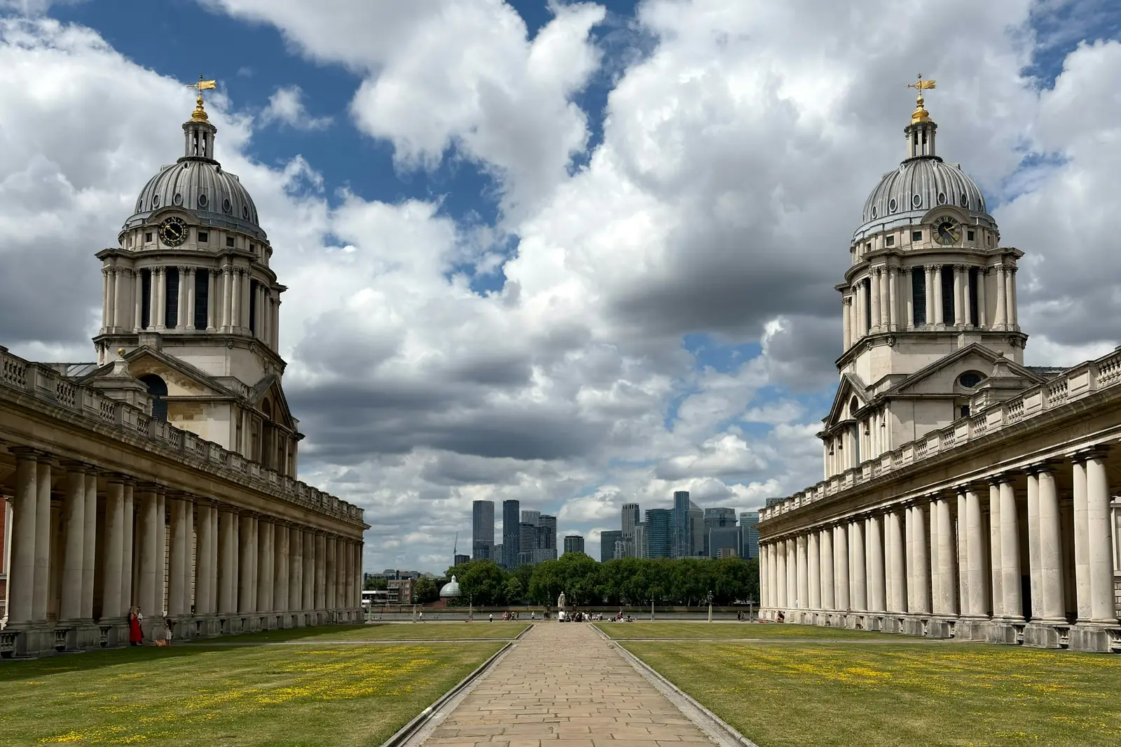 Family on the hill in Greenwich Park with the Queen's House and Canary Wharf behind them