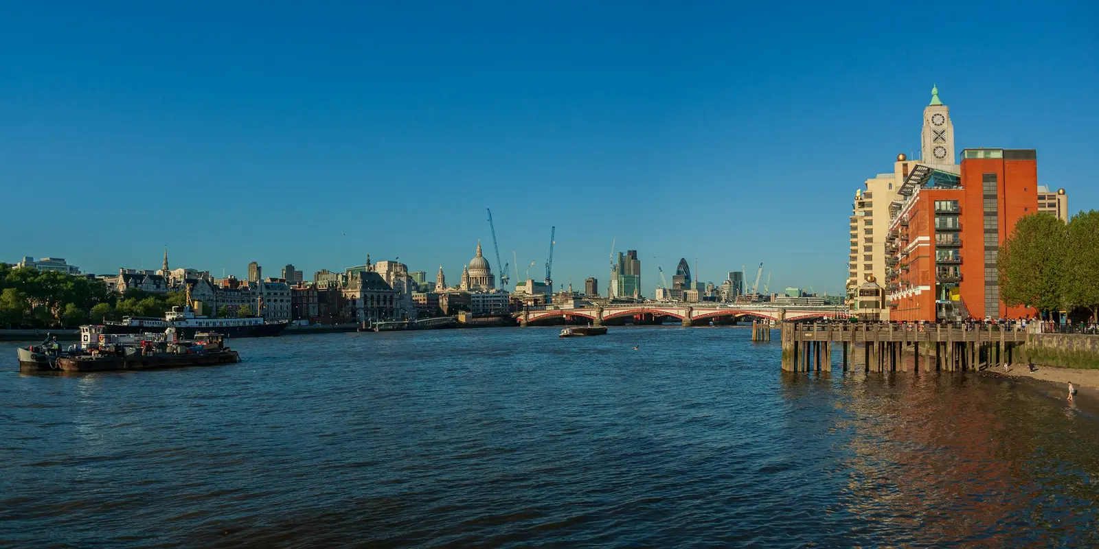 Couple on a footbridge over the Thames at blue hour with the lit London skyline behind