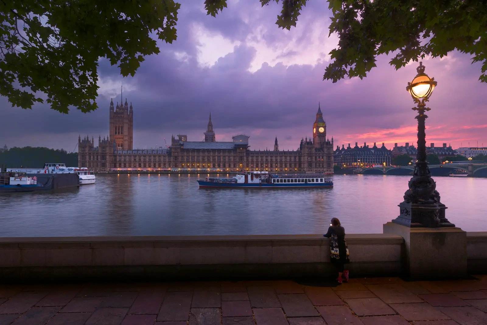Couple on Westminster Bridge at sunrise with Elizabeth Tower lit behind them