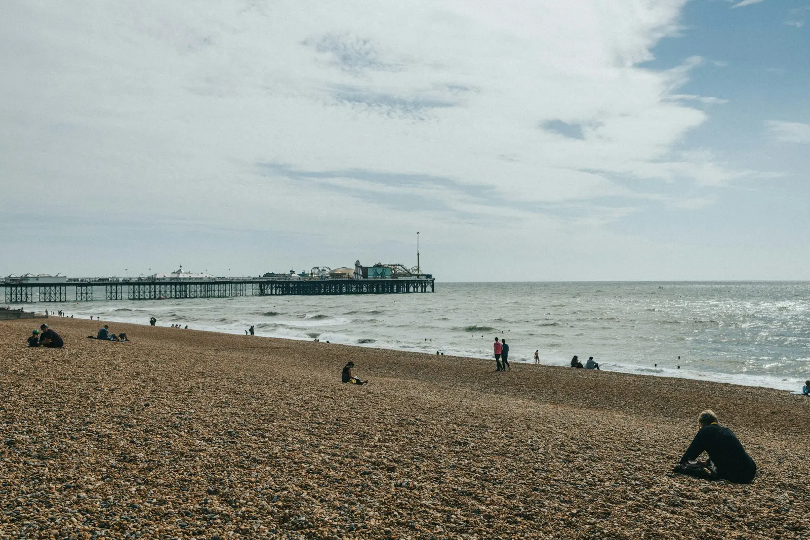 A couple on Brighton beach at sunset with the silhouette of the West Pier ruins behind them
