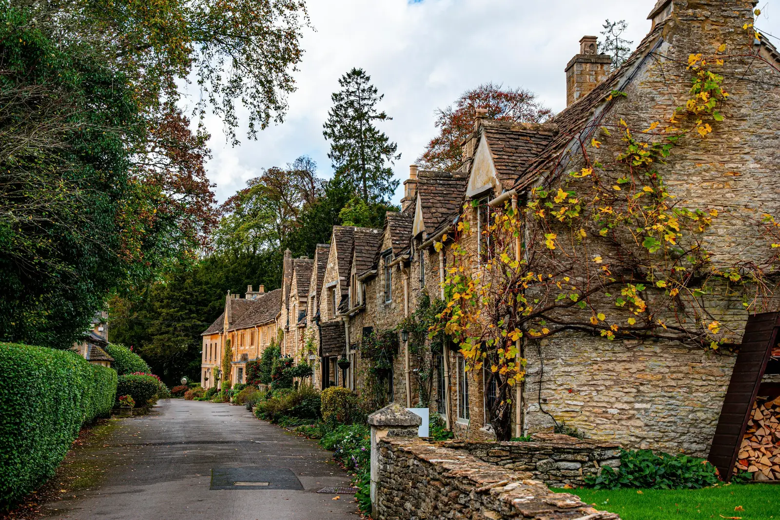 Honey-coloured stone cottages of Arlington Row in Bibury beside a water meadow in early morning light