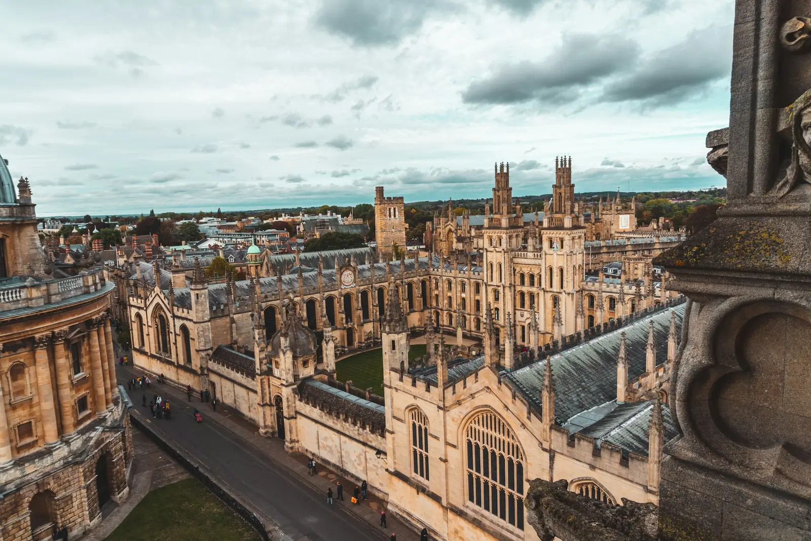 A couple walking across Radcliffe Square in Oxford with the Radcliffe Camera behind them in soft morning light