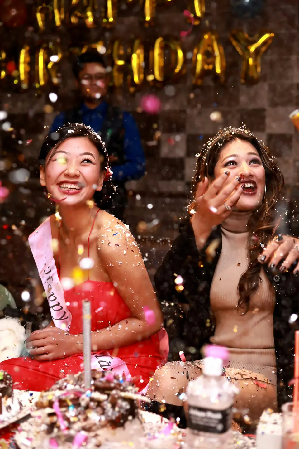A woman laughing beside number balloons at her birthday photoshoot