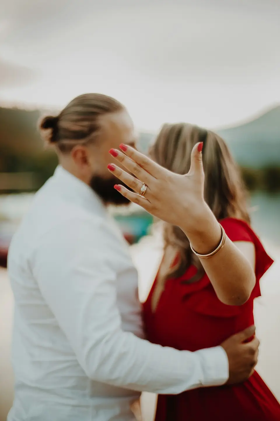An engaged couple laughing together on a stone bridge