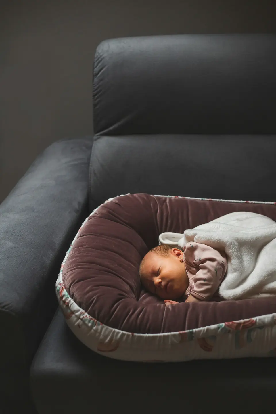 A parent holding a sleeping newborn in soft window light