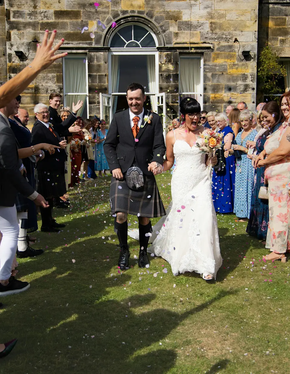 A couple leaving their wedding ceremony under a shower of confetti